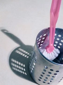 Pink handled kitchen scrub brush inside silver aluminum metal container. Stock Photos