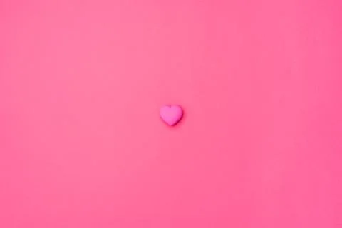 Pink heart isolated in the center on an empty colorful pink background. Symbol Stock Photos
