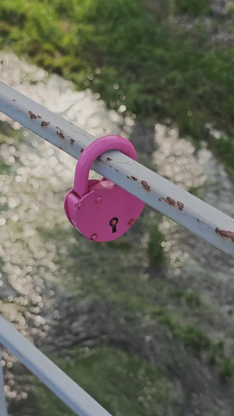 Pink heart shaped padlock symbolizing eternal love hanging on a rusty metal Stock Footage 342611003