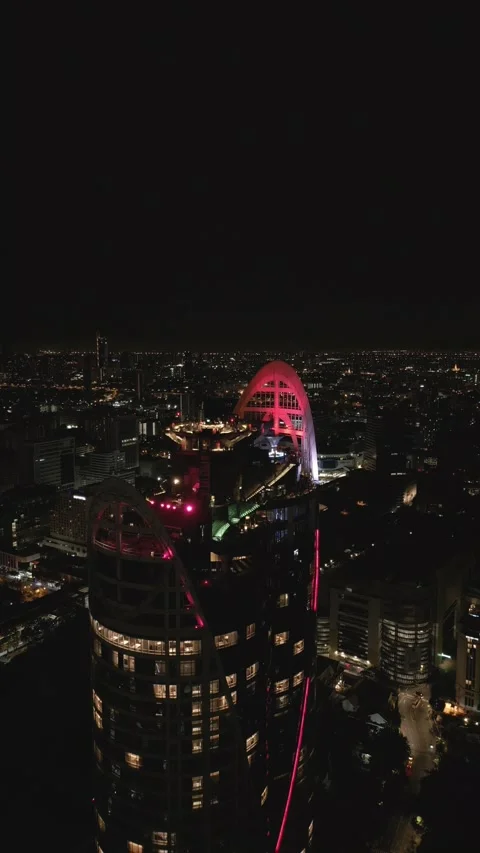 Pink Illuminated Skyscraper Arching Over Night Cityscape in Bangkok, Thailand Stock Footage 333597830