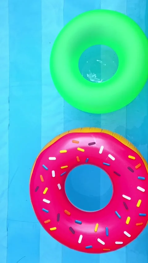 Pink inflatable donut and vivid green rings in a swimming pool Stock Footage 304656530