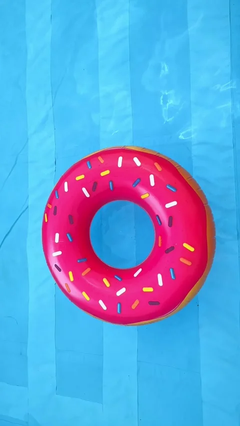 Pink inflatable donut ring in a swimming pool with clear blue water Stock Footage 304656549