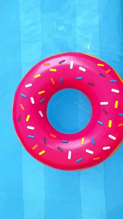 Pink inflatable donut ring in a swimming pool with clear blue water Stock Footage 304656768