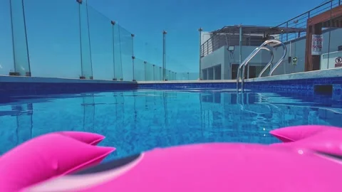 Pink inflatable mattress floating on rooftop swimming pool in summer, POV Stock Footage 310574897
