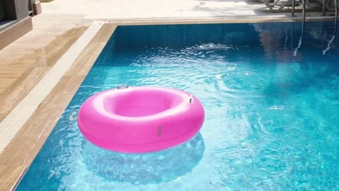 Pink inflatable ring floating in the swimming pool with blue water. Traveling Stock Footage 166017688