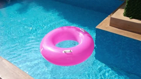 Pink inflatable ring floating in the swimming pool with blue water. Traveling Stock Footage 172542374