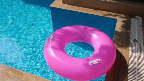 Pink inflatable ring in the swimming pool. Refreshing blue water. Top view. Copy Stock Footage 160549194