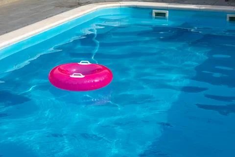Pink Inflatable Swim Ring in Empty Pool on Hot Summer Day for Childrens Wat.. Stock Photos