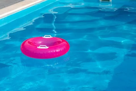 Pink Inflatable Swim Ring in Empty Pool on Hot Summer Day for Childrens Wat.. Stock Photos