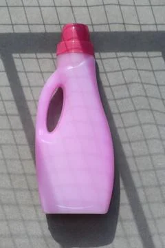 Pink laundry detergent bottle on a grid-patterned surface, clean and organi.. 스톡 사진