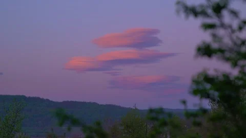 Pink lenticular clouds over hills at sunset in summer. Stock Footage 345077680