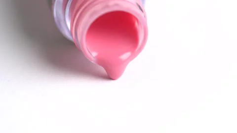 Pink lipgloss flows out of an overturned bottle. Coral lipgloss pouring on .. Stock Footage 262417627