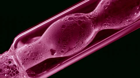 Pink liquid condensing on bulb lab condenser black background Stock Footage 335874417