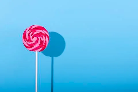 Pink Lolipop candy with shadow on pastel blue background Stock Photos