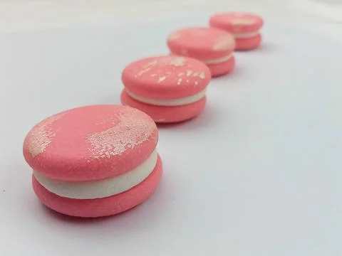 Pink macarons in diagonal row on white background Stock Photos
