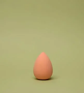 Pink makeup sponge with rounded shape on green background Stock Photos