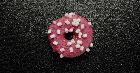 Pink marshmallow glazed donut rotating on a dark background Stock Footage 342737252