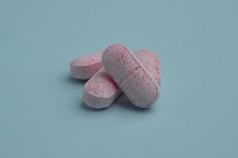 Pink medicine pill tablet float on blue background. Ideal for healthcare, p.. Stock Photos