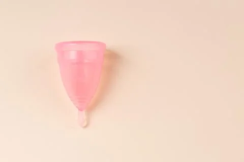 Pink Menstrual cup on bright beige background Stock-Fotos