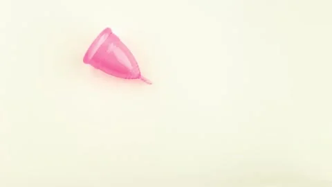 Pink Menstrual Cup is moving round on the pastel yellow background Stock Footage 164918380