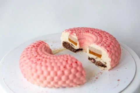 Pink mousse cake in the form of a donut in circles cut in half. Stock Photos