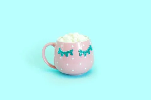 Pink mug with white polka dots with blue closed eyes with coffee and marshmal Stock Photos