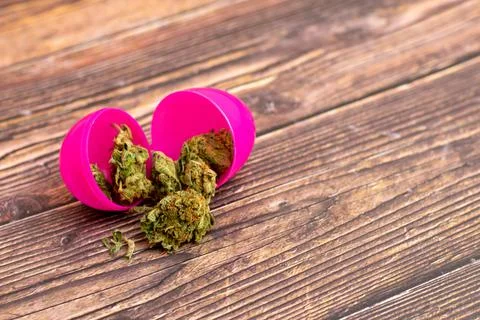 A Pink Open Easter Egg With Cannabis Coming Out of It Stock Photos