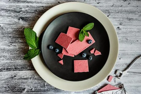 Pink or ruby chocolate, trendy dessert on a black plate on wooden grey backround Stock Photos