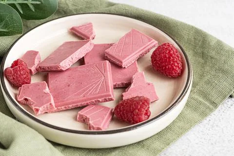 Pink or ruby chocolate, trendy dessert on a white plate with raspberries Stock Photos