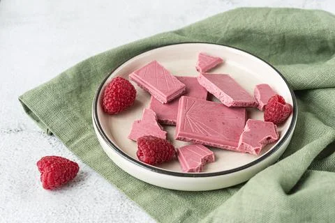 Pink or ruby chocolate, trendy dessert on a white plate with raspberries Stock Photos