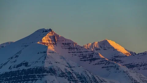 Pink orange alpenglow over two snow covered mountains Stock Footage 73011235