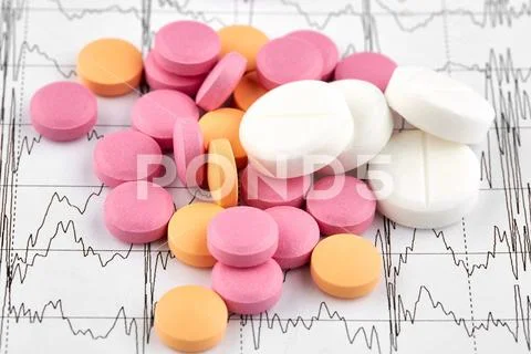 Pink, orange and white pills on EKG graph Stock Photos