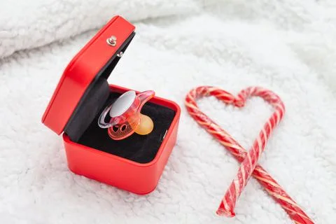 Pink pacifier in a red box on a white background Stock Photos