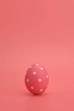 A pink painted Easter egg in white peas stands on a pink background. Stock Photos