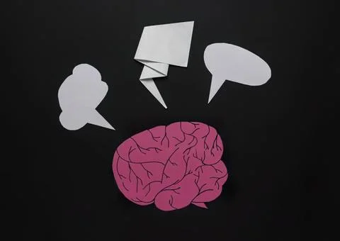 Pink paper brain with speech bubbles on black background Stock Photos