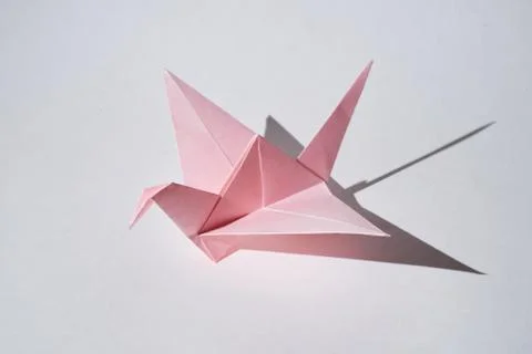 Pink paper dragon figurine stands on a white background in hard light. Stock Photos