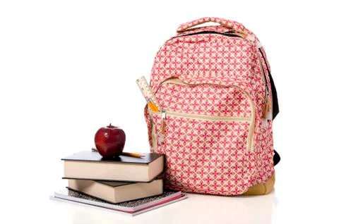 Pink patterned back pack with supplies and an apple Stock Photos