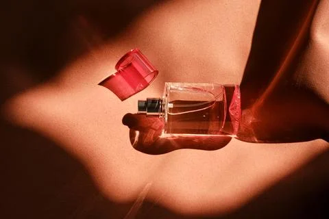 A pink perfume bottle on a soft reddish background. Stock Photos