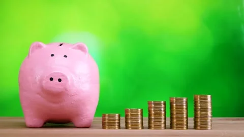 Pink piggy bank and stack of golden money coin on wooden desk Stock Footage 281140214