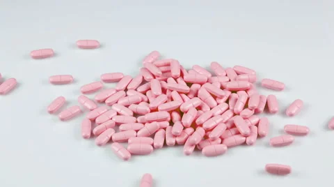 Pink pills falling on the table Stockbeeldmateriaal 41853600