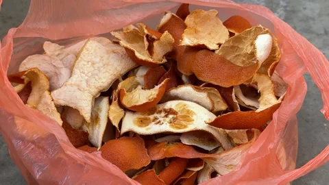 Pink plastic bag full of dried orange peels on concrete floor Video stock 342438218