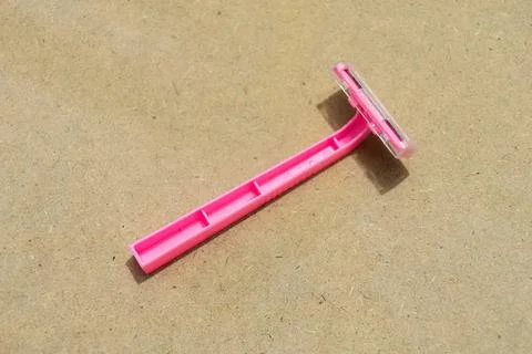 A pink plastic disposable razor featuring a single blade and protective cap.. Stock Photos