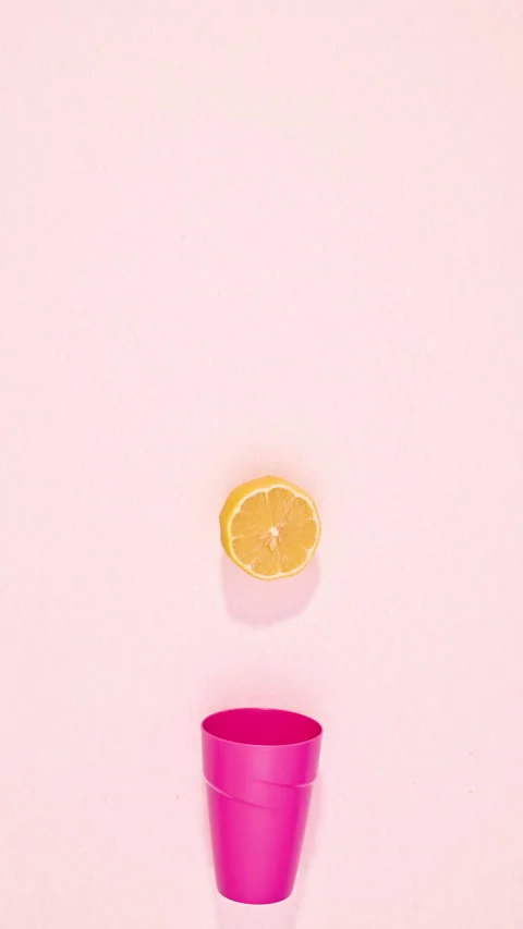 Pink plastic glass catching falling lemons on pink background. stop motion Stock Footage 280132698