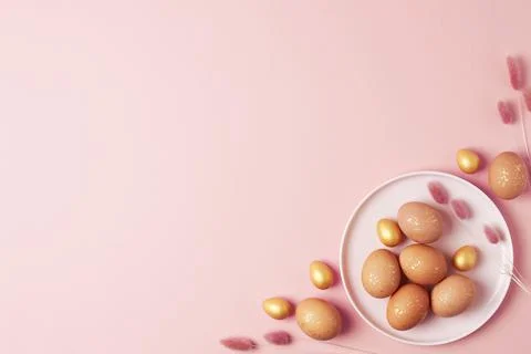 Pink plate with easter eggs and flowers on pink background. Flat lay, copy sp Stock Photos