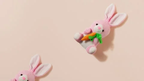 Pink plush little Easter bunny with a red carrot on a pastel beige background Stock Footage 149072919
