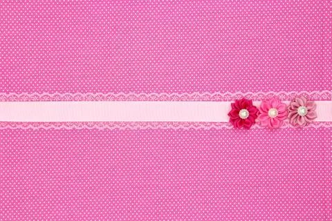 Pink polka dot textile background with ribbon and flowers Stock Photos