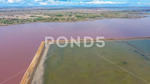 Pink pond in France separated the road from the lagoons for evaporation of sa Stock Photos