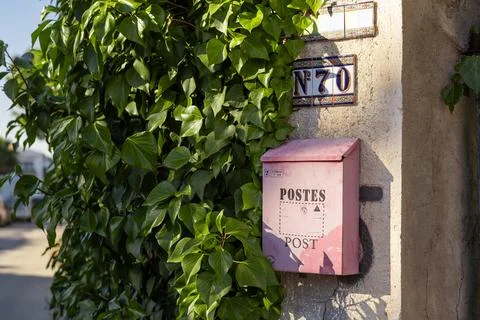 A pink post office box mounted on a wall in Torrevieja, Spain, surrounded b.. Foto stock