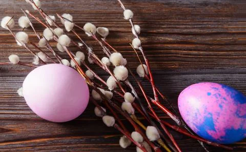 Pink, purple easter eggs, willow branches on a dark wooden background, top vi Stock Photos
