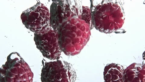 Pink raspberry fall splashed water goblet closeup. Sparkling clear aqua berries Stock Footage 219270059